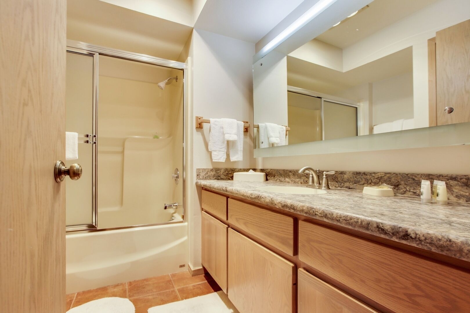 Une salle de bain moderne avec une douche à l’italienne, un grand miroir et un comptoir en granit.