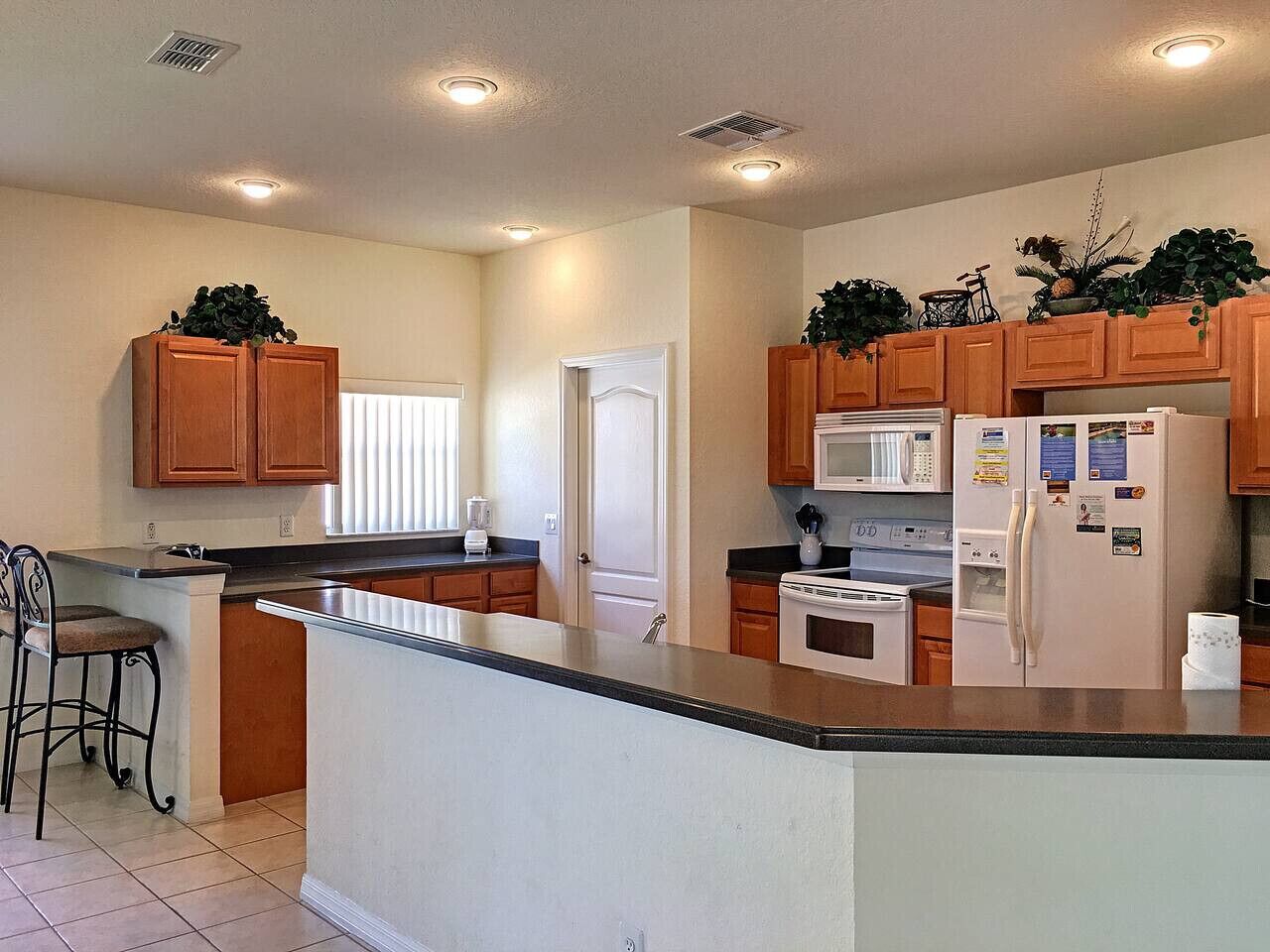 A modern kitchen with wooden cabinets, a central island, a microwave, stove, and refrigerator.