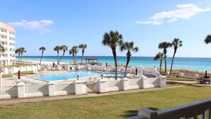 Ein Poolbereich mit Blick auf das Meer, umgeben von Palmen und einem weißen Zaun.