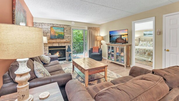 A living room with a fireplace, sofa, coffee table, and television. - two bedroom condo sleeps 7 persons (Gatlinburg)