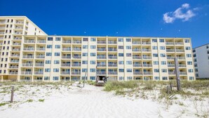 Un hotel a più piani con facciata uniforme, balconi e una spiaggia sabbiosa in primo piano.