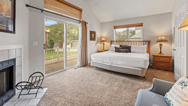 Ein Schlafzimmer mit Bett, Stuhl, Nachttisch, Lampe, Kamin und Blick ins Freie.