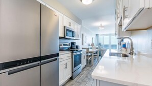 A modern kitchen with stainless steel appliances, a central island, and a view to the dining area.