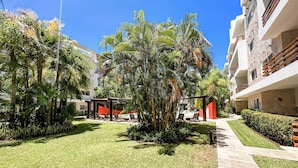 Un patio bien cuidado con piscina, sillas de descanso y abundante vegetación.