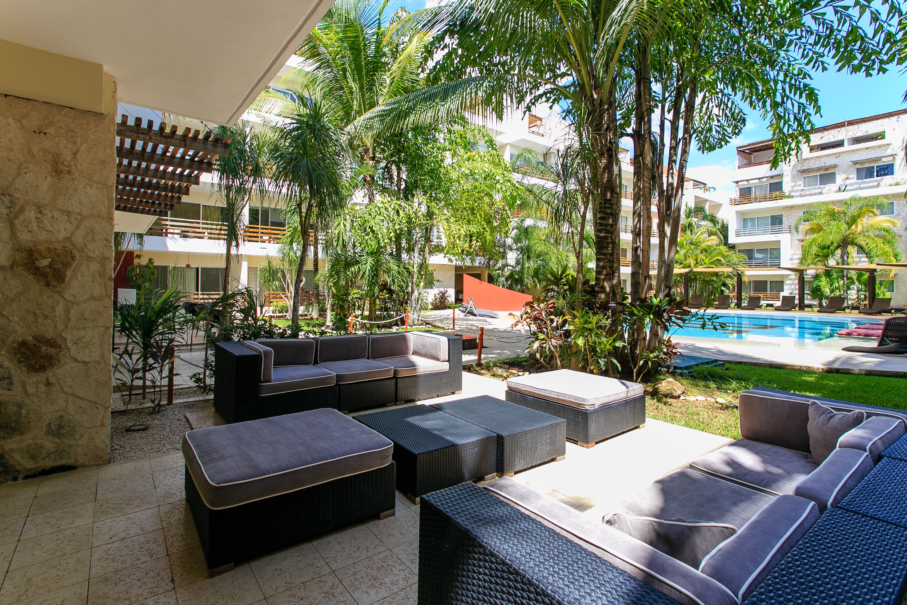 A poolside area with outdoor seating, palm trees, and a view of a swimming pool.