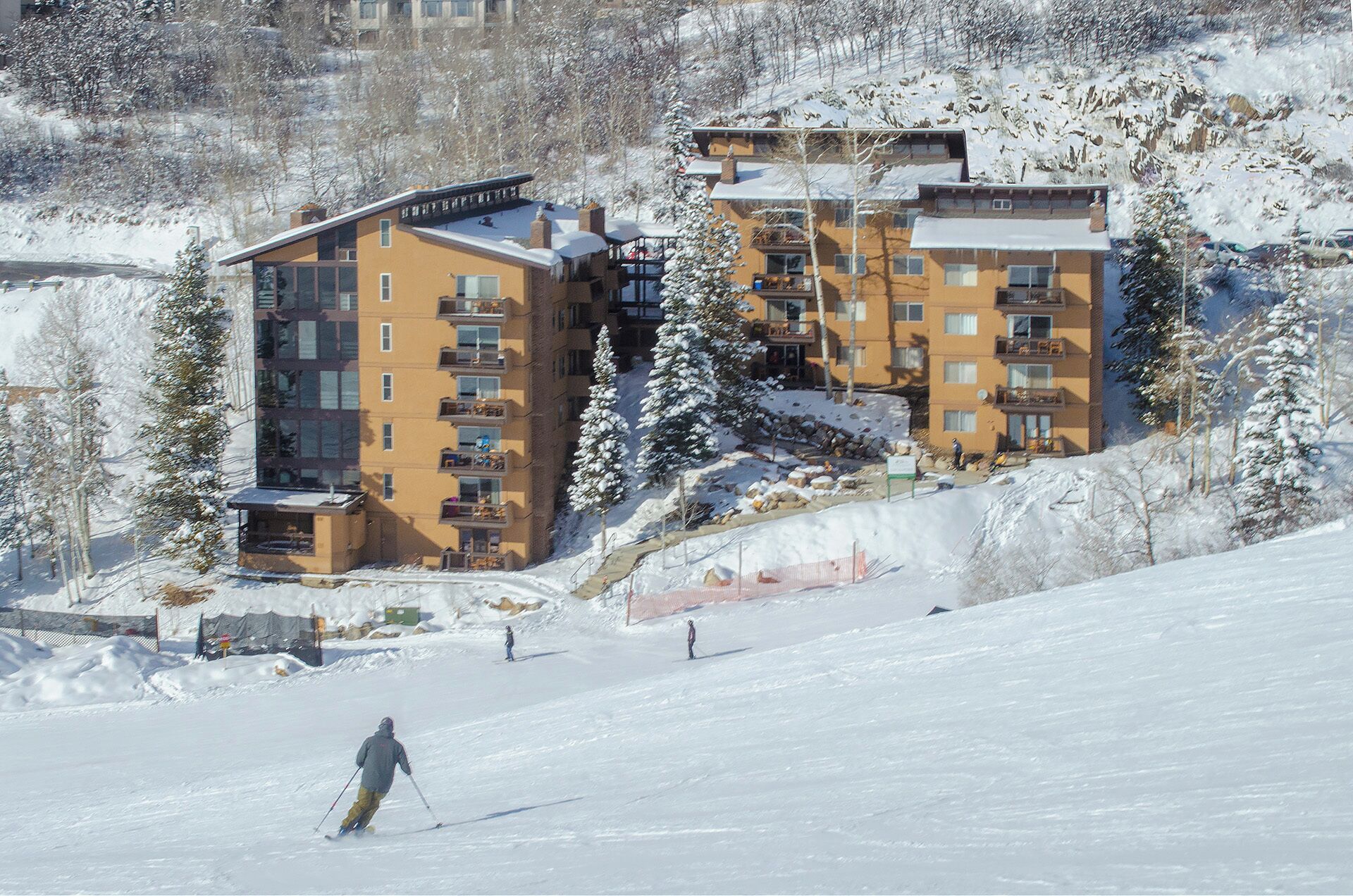 Une station de ski avec des bâtiments à plusieurs étages, des pistes de ski et des arbres couverts de neige.