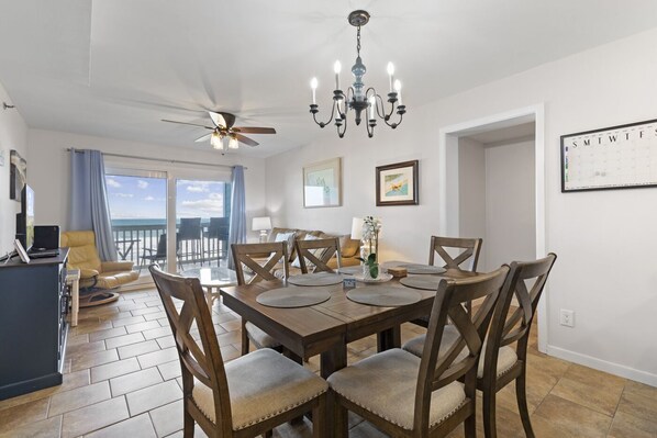 A dining area with a wooden table and chairs, a ceiling fan, and a chandelier. - Oceanfront North Myrtle Beach condo, smaller complex (North Myrtle Beach)