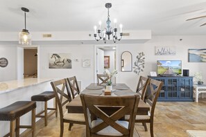 A dining area with a wooden table and chairs, a chandelier, and artwork on the walls.