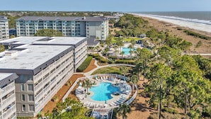 Een hotel met meerdere verdiepingen, een zwembad op het dak en uitzicht op het strand.