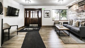 A modern living room with a sofa, chairs, a coffee table, a TV, and a wooden floor. - Managed by Park City Lodging-Walking Distance to Main Street & Lift-On Shuttle (PARK CITY)