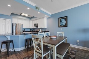 A kitchen with white cabinets, a central island, and a dining table with chairs.