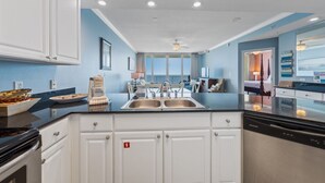 A modern kitchen with white cabinets, a black countertop, and stainless steel appliances. - Beachfront w/ Expansive Gulf Front View | Pool, Outdoor Grills, Sauna | Sleeps 7 (Gulf Shores)