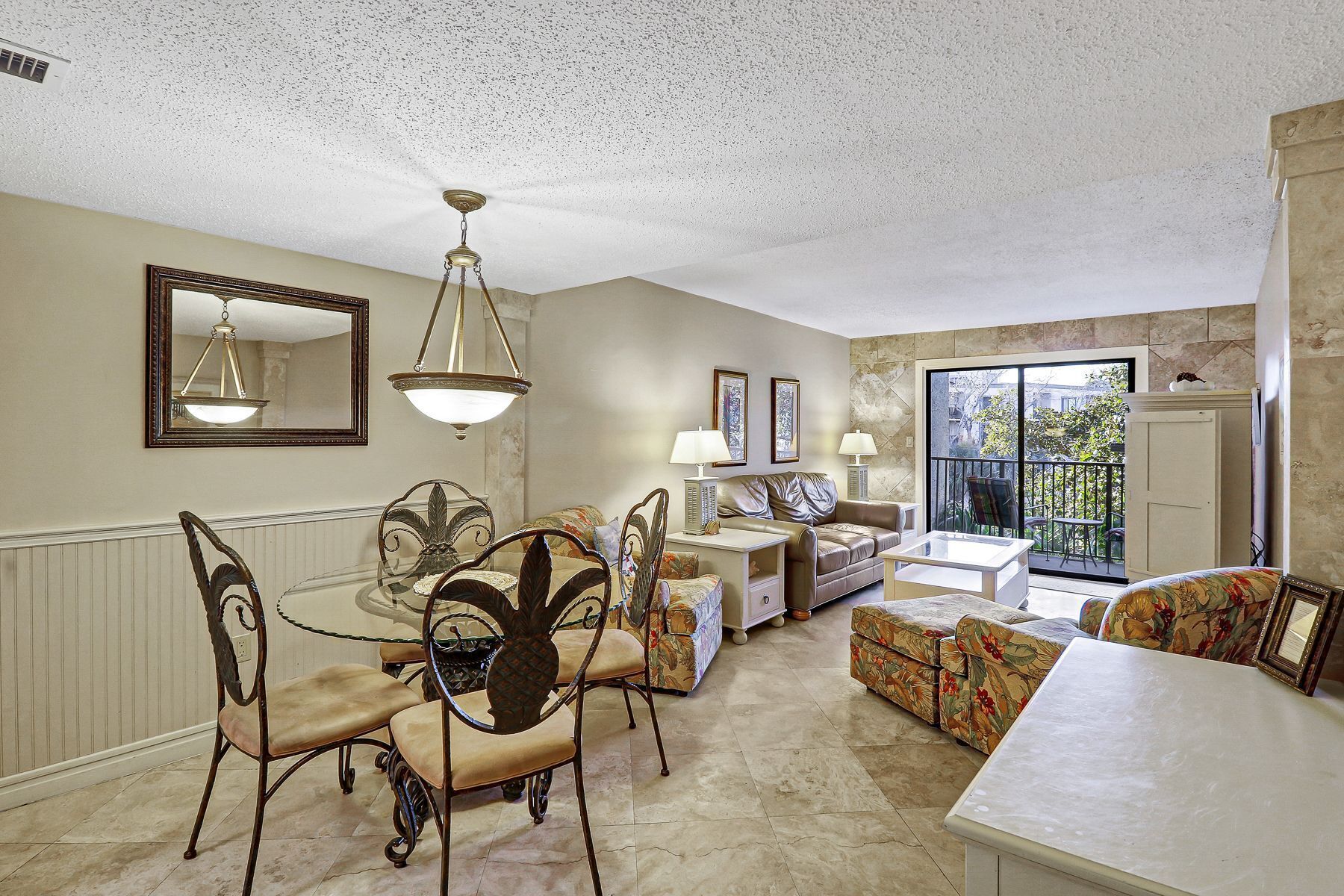 A spacious living room with a dining area, a large window with a view, and a ceiling with a textured finish.