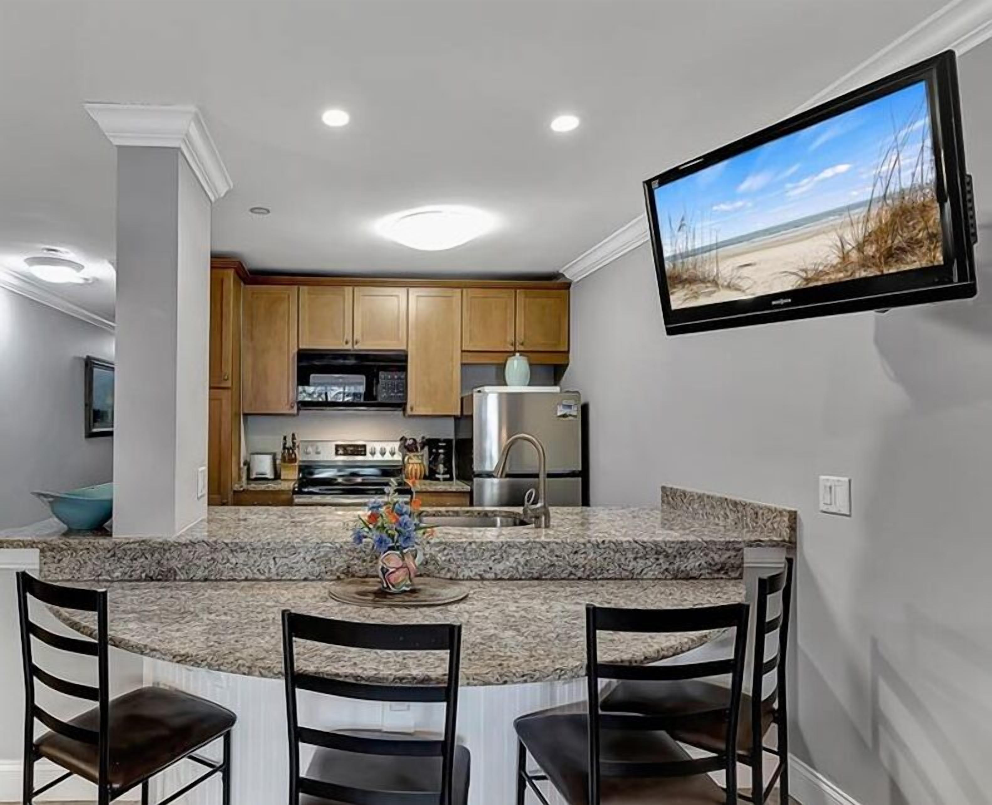 A modern kitchen with granite countertops, wooden cabinets, and a built-in oven.
