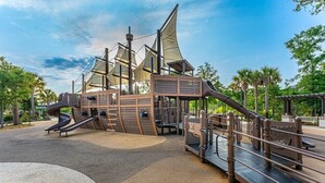 A playground with a ship-themed play structure, including slides and climbing areas. - Beautiful Beachside Villa! Oceanfront Pool (Hilton Head)