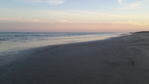 Una playa con una extensa orilla arenosa y olas suaves.