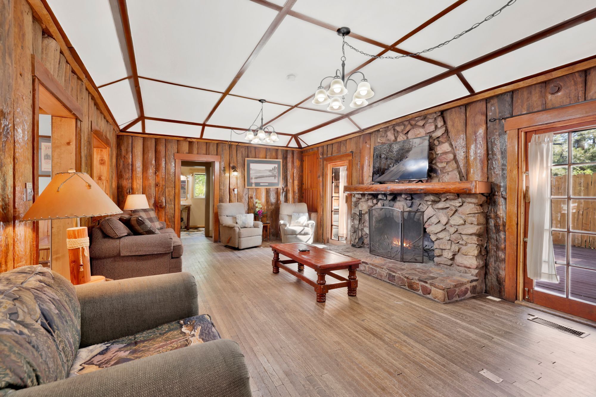 Cozy cabin living room with a stone fireplace, comfy seating, and rustic wood details—perfect for relaxing evenings, movie nights, and unforgettable mountain getaways.