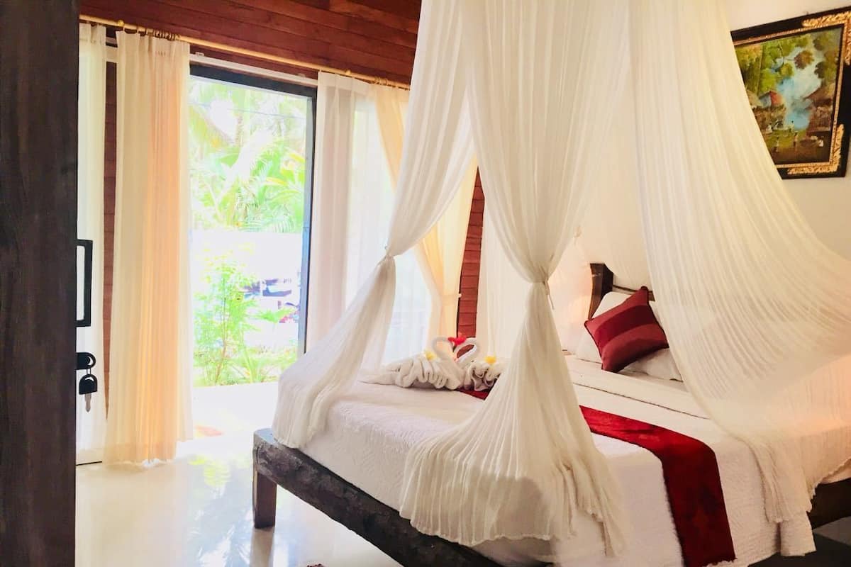 A bed with a canopy, pillows, and a red blanket.