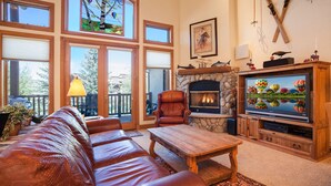 Una sala de estar acogedora con un sofá de cuero, una mesa de centro de madera, una chimenea y un televisor.