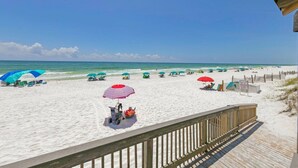 A beach with umbrellas and lounge chairs, a wooden deck, and a clear blue sky. - El Matador 431 by Alicia Hollis Rentals FREE TICKETS! $300/Day (Fort Walton Beach)