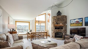 Ein gemütliches Wohnzimmer mit Kamin aus Stein, einem Essbereich mit Tageslicht und Blick ins Freie.