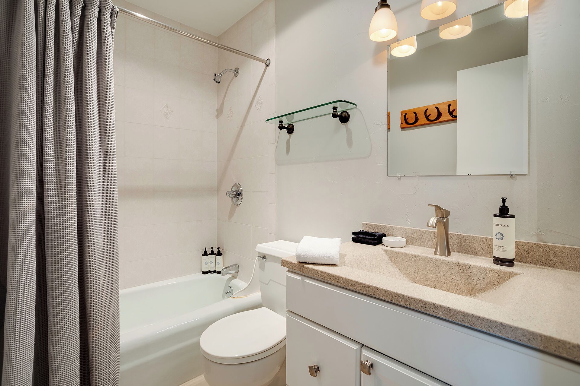 Une salle de bain moderne équipée d’une baignoire, de toilettes et d’un meuble-lavabo avec un évier et un miroir.