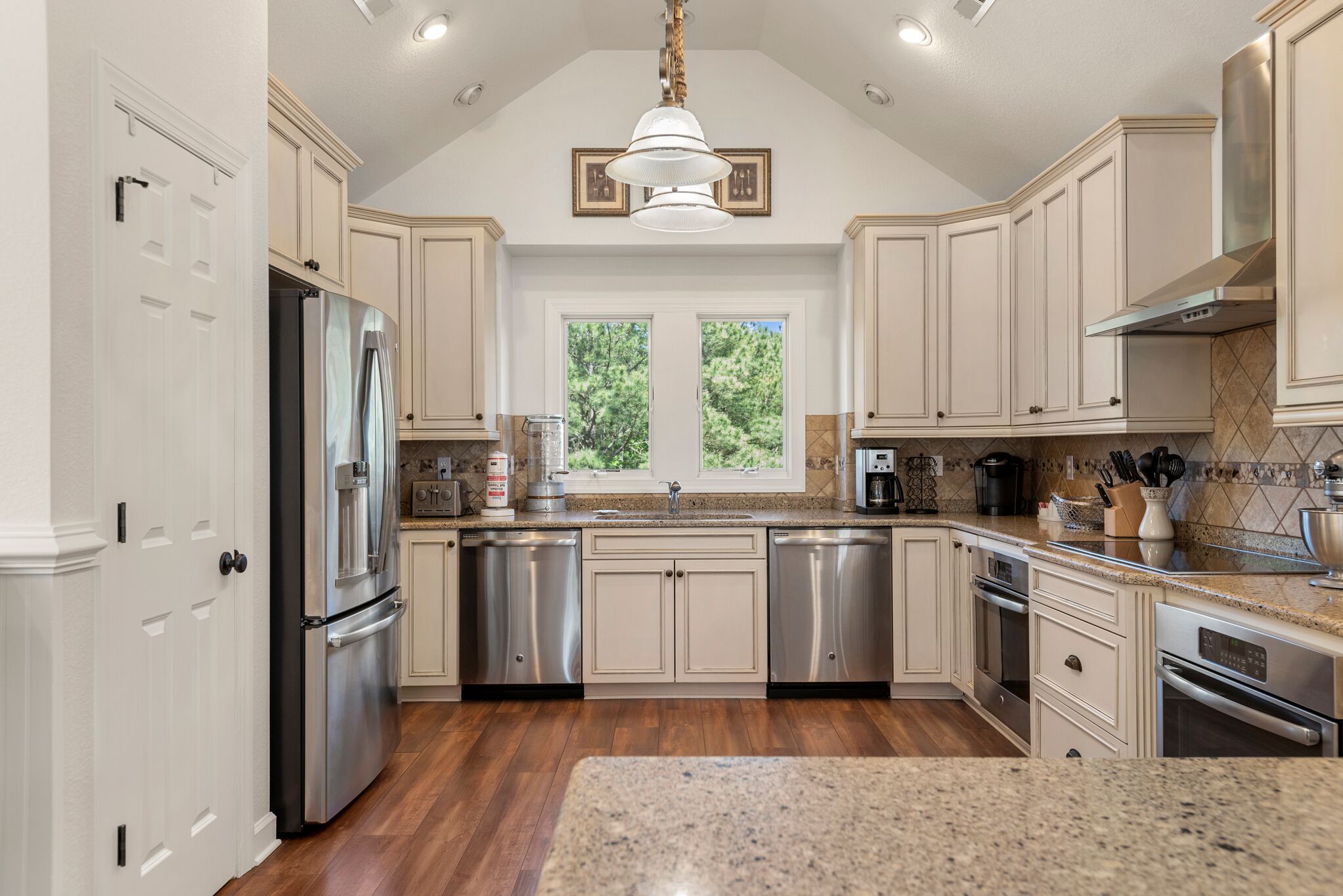 A spacious kitchen with stainless steel appliances, light-colored cabinetry, and a large window providing natural light.