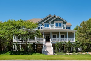 A two-story house with a front porch, a staircase leading to the entrance, and a well-maintained lawn.