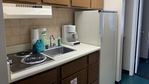 A kitchen with wooden cabinets, a coffee maker, a sink, and a stove.
