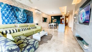 A modern living room with a green sofa, a coffee table, and a large abstract painting on the wall. - Trendy 2 Bedrooms + Near Mamita's Beach + Seps from 5th av- Playa del Carmen (Playa Del Carmen)