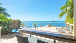 A terrace with a view of the sea, outdoor seating, and potted plants. - Beachfront, Poolside, Kayaks for snorkeling the reef! (West End)