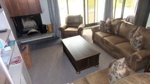 A living room with a fireplace, leather sofas, and a coffee table. - Snowflake Lodge conveniently located ski in/out sleep 6 Close to Restaurants (Copper)