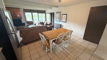 Un espacio habitable compacto con comedor, kitchenette y un ventanal que ofrece vistas al exterior.