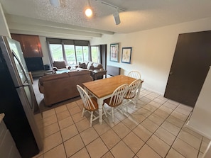 A compact living space with a dining area, kitchenette, and a large window providing a view of the outdoors.