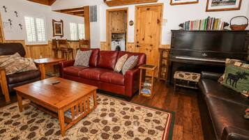 A cozy living room with a red leather sofa, wooden coffee table, and a piano.