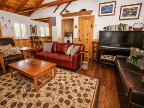 Uma sala de estar aconchegante com um sofá de couro vermelho, uma mesa de centro de madeira e um piano.