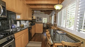 Una cucina con mobili in legno, un piano di lavoro in granito, un fornello e un'area pranzo con tavolo e sedie.