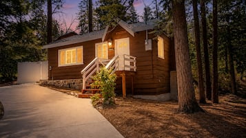 A wooden cabin with a covered porch and a staircase leading to the entrance.