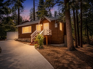 A wooden cabin with a covered porch and a staircase leading to the entrance. - Grizzly Bear - Moonridge | Hot Tub + Fireplace + Forest Views (Big Bear Lake)