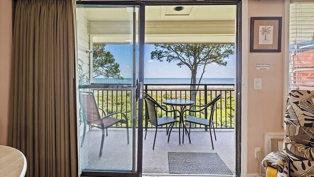 Une pièce dotée d’une porte-fenêtre coulissante donnant sur un balcon aménagé avec du mobilier d’extérieur.