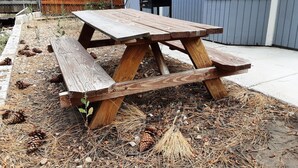 Uma mesa de piquenique de madeira com bancos num quintal.