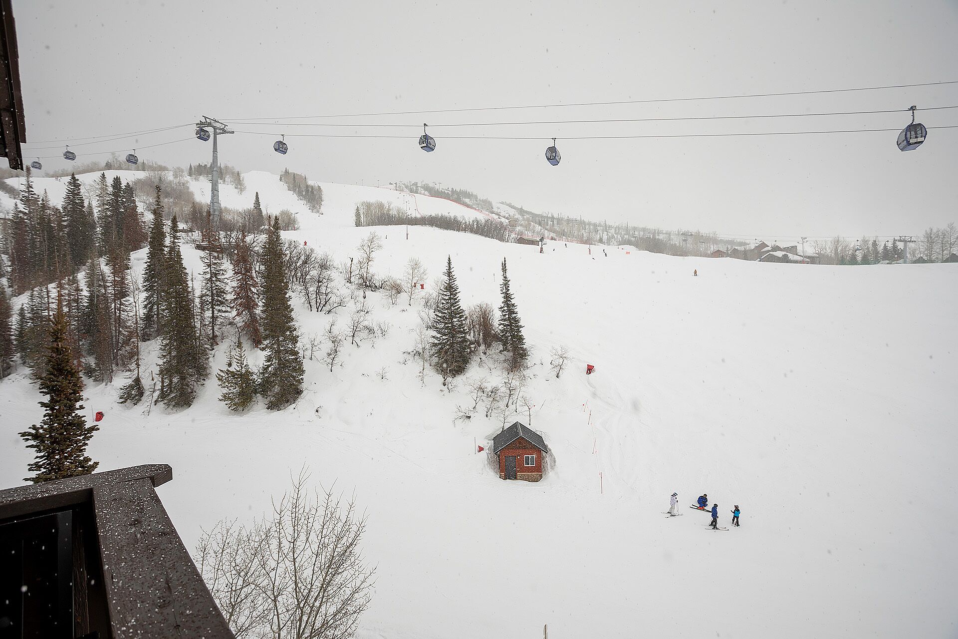 A snowy mountain scene with a ski lift, a cabin, and skiers.