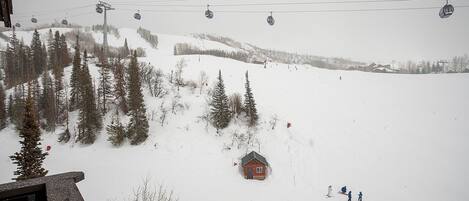 A snowy mountain scene with a ski lift, a cabin, and skiers.