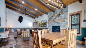 A rustic interior with a stone fireplace, wooden dining table, and seating area.
