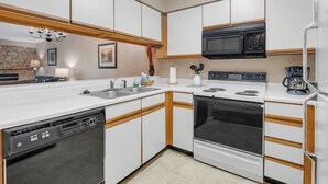 A modern kitchen with white cabinets, a black microwave, a stove, and a dishwasher. - two bedroom condo sleeps 6 persons (Gatlinburg)