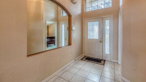 A hallway with a large mirror, a piano, and a door with a stained glass window. - Luxury Pool Home, 2 Master Suites, Lakeview & Games Room. Disney 3 Miles (Kissimmee)