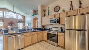 A modern kitchen with wooden cabinets, stainless steel appliances, and a large island. - Luxury Pool Home, 2 Master Suites, Lakeview & Games Room. Disney 3 Miles (Kissimmee)