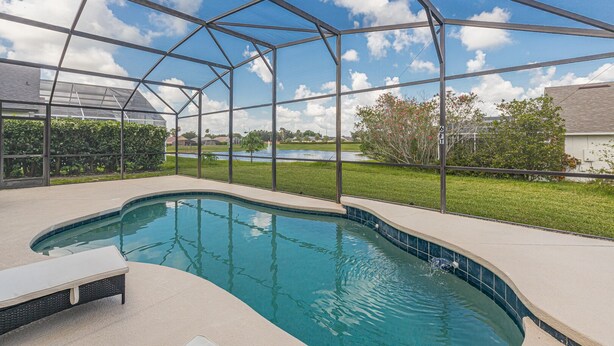 A covered swimming pool with a view of a lake and surrounding greenery. - Luxury Pool Home, 2 Master Suites, Lakeview & Games Room. Disney 3 Miles (Kissimmee)