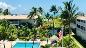 A resort with a swimming pool, palm trees, a view of the ocean, and an American flag. - Multiple GULF VIEWs (Sanibel)