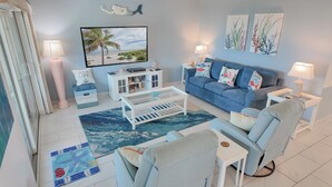 A living room with a sofa, coffee table, and a television displaying a beach scene. - Multiple GULF VIEWs (Sanibel)